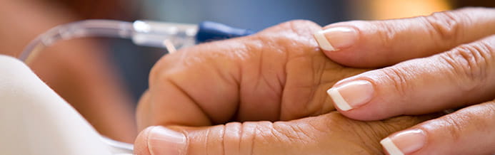 Woman holds man's hand during chemo