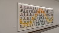 Over one hundred cartoon faces of individuals of various skin colors, hair colors, hair styles, accessories, and poses, with a wavy yellow orange curved line across some of their faces