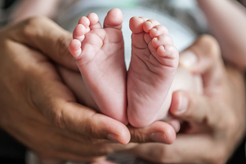 parent hands holding infant feet