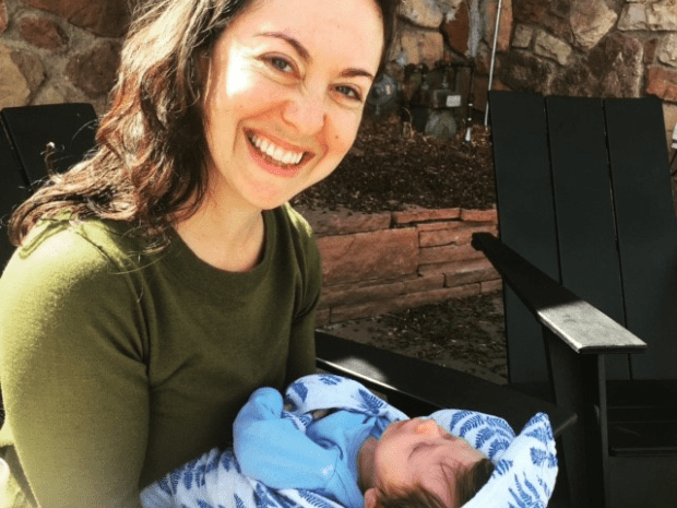 Diana Smith wearing a green shirt pictured smiling, holding baby dressed in blue
