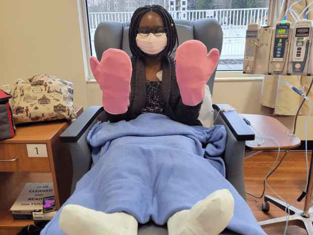 Keziah pictured laying on recliner, wearing pink mittens