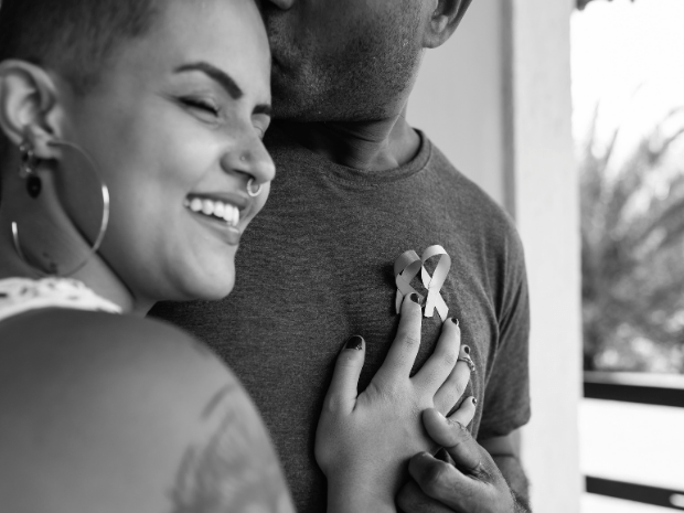 Black and white image of a person hugging another person wearing two cancer ribbons