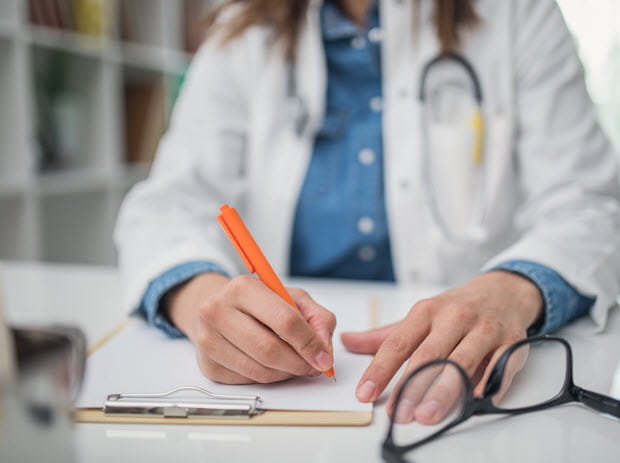 Doctor writing on clipboard