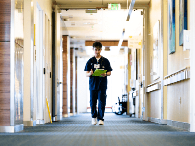 Image of Peter Tran walking down a hallway, holding a green clipboard